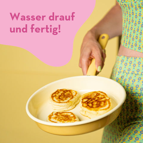 Frauenkörper hält Pfanne mit Reoat-Pancakes, darüber steht 'Wasser drauf und fertig' - SEO-optimiert für Reoat.