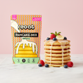 reoat Pancake-Mix Original als vegane Backmischung: Packung „reoat PANCAKE-MIX ORIGINAL“ neben einem Stapel fluffiger veganer Pancakes mit cremigem Topping/Sirup, garniert mit Banane, Himbeeren, Blaubeeren und Minze auf Marmortisch vor rosé Hintergrund – schnell zubereitet (nur Wasser), ideal für Frühstück und Brunch, veganer Pancake-Teig zum Anrühren aus dem reoat Onlineshop.